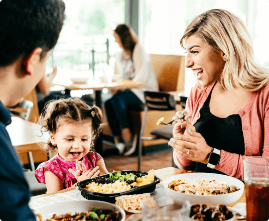 a family laughing while eating food at noodles & company
