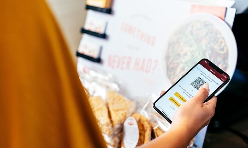 Person with smartphone uses Noodles & Company franchise app to order food