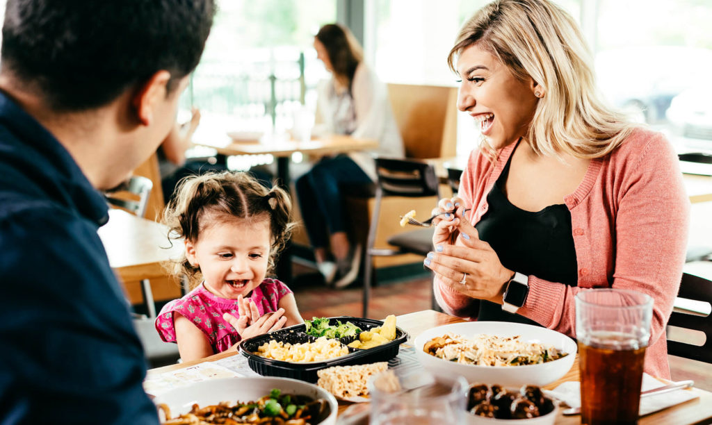 A father, a mother, and a little girl dine at a Noodles & Company franchise restaurant