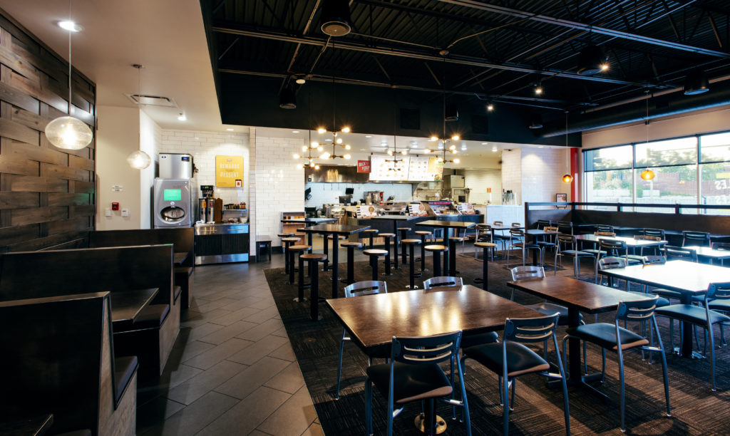 The interior of a restaurant franchise with tables, booths, and an open kitchen