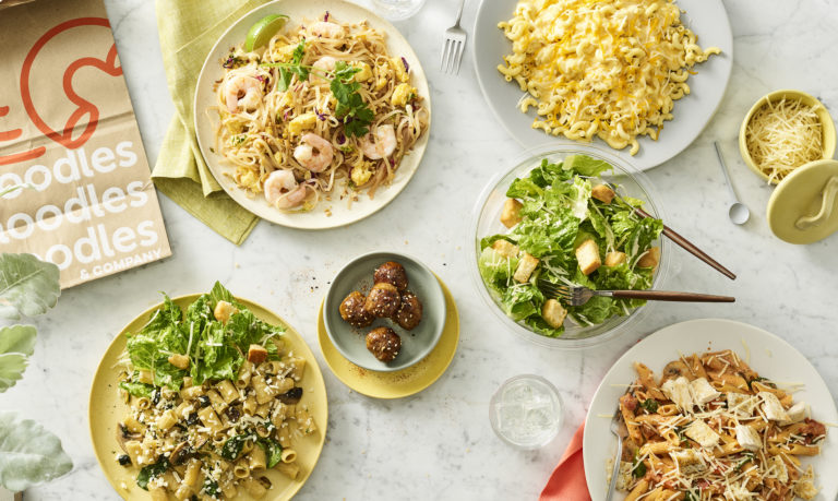 Image of Noodles & Company pasta and salad dishes on a marble countertop